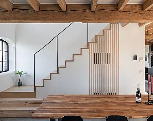 Moderne eetruimte in Vakantiehuis in Wachtebeke, Oost-Vlaanderen, Belgi, met houten tafel en stijlvolle trap.