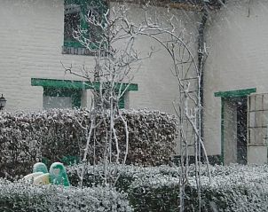 Sneeuw bedekt de tuin van Vakantiehuisje in Herderen, een charmant vakantiehuis in het winterse Limburg, Belgi.